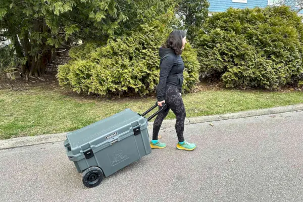 Una persona che trasporta all'esterno il frigorifero portatile Pelican 65QW Elite