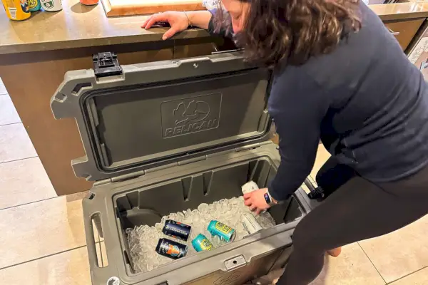 Una persona che riempie il frigorifero portatile Pelican 65QW Elite con ghiaccio e bevande
