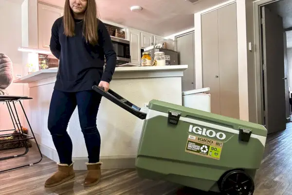 Una persona che fa rotolare l'Igloo ECOCOOL Roller Cooler - 90 qts