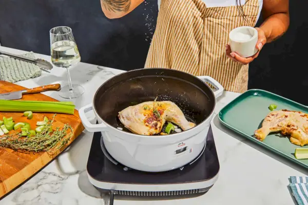 Eine Person kocht Hühnchen in der gusseisernen runden 5,5-Quart-Cocotte von Staub