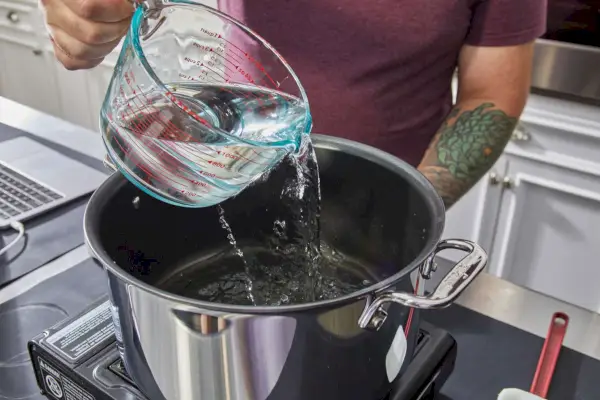Wasser wird in den All-Clad D3 Edelstahl-Topf mit dreilagigem, 10-teiligem Antihaft-Kochgeschirrset gegossen