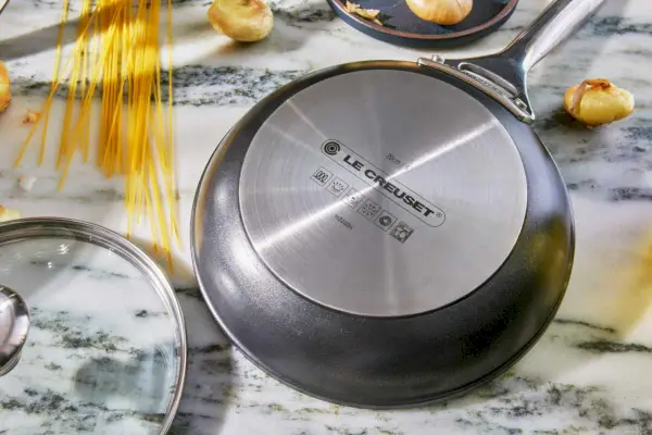 Die Unterseite der Le Creuset Toughened Nonstick Pro 10-teiligen Kochgeschirr-Pfanne ist auf der Arbeitsplatte abgebildet