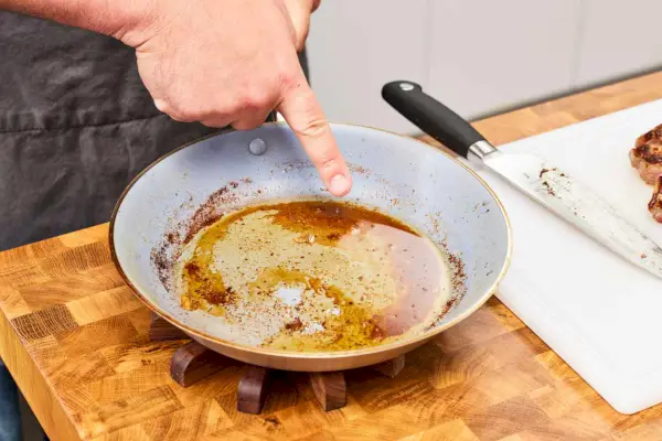 Die Rückstände auf dem Material der beschichteten Pfanne nach dem Garen von Fleisch