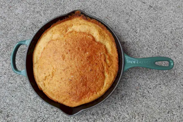 Klassische Bratpfanne mit Gusseisengriff von Le Creuset mit gebackenem Kuchen im Inneren, ausgestellt auf einer Theke