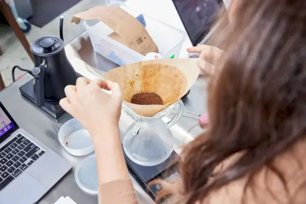 Chemex クラシック シリーズ コーヒーメーカーにコーヒーの入ったフィルターを入れる人