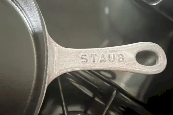 Eine Nahaufnahme des Logos auf der traditionellen 11-Zoll-Tiefpfanne aus Gusseisen von Staub