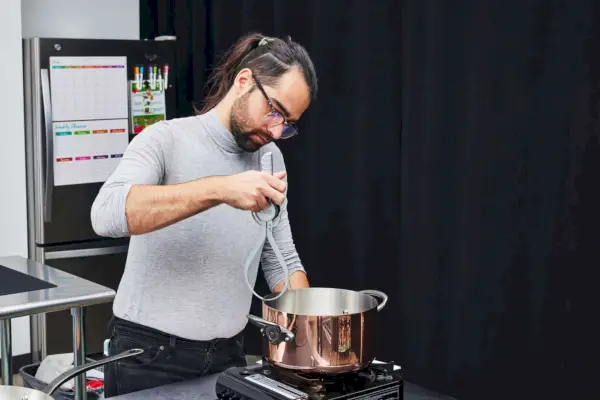 Eine Person untersucht das 10-teilige Kochgeschirrset Mauviel Copper Mâ200 CI