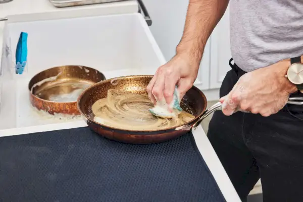 Eine Person wäscht die Pfanne des Hestan CopperBond 10-teiligen Kochgeschirr-Sets