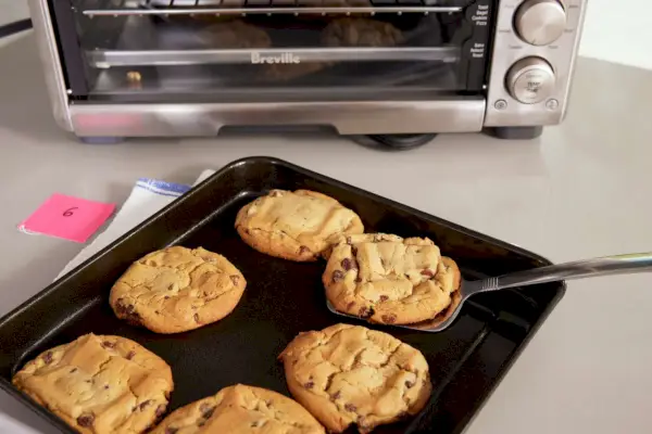 Breville The Compact Smart Oven の隣のカウンターに並べられたクッキーがいっぱいのベーキングシート