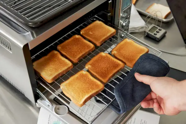 Breville スマート オーブン エアフライヤーからトーストのトレイを取り出す人