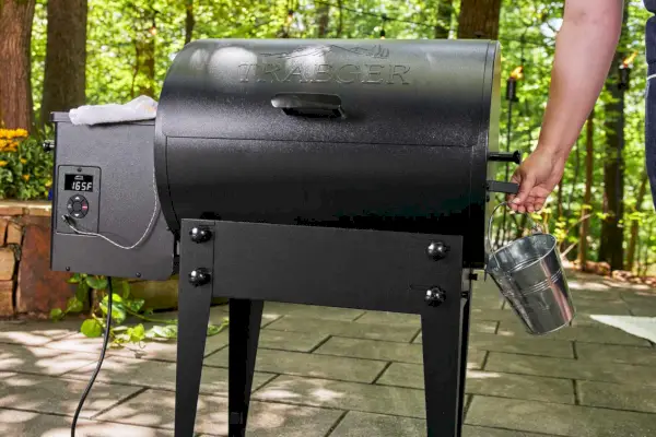 Traeger TFB30KLF Tailgater Pellet Grill에서 작은 버킷을 손으로 제거하는 모습