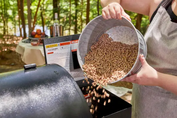 Traeger Pro Series 780 목재 펠릿 그릴 및 흡연기에 펠릿을 붓는 사람