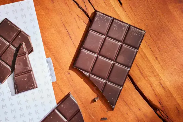 Barras de chocolate amargo K+M Hacienda Victoria desembrulhadas em um balcão de madeira