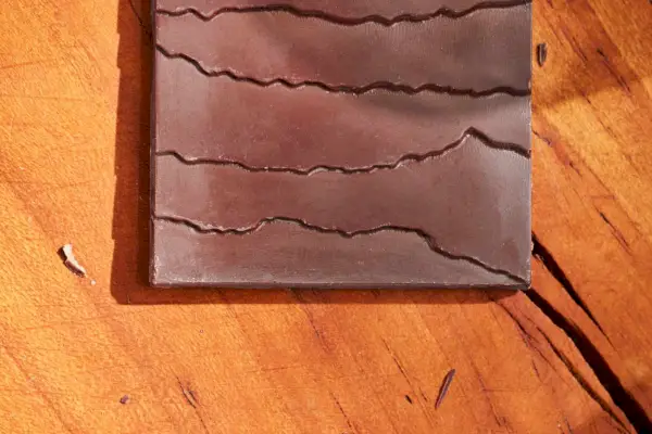 Barra de chocolate amargo clássica Raaka Filipinas 71% desembrulhada em uma mesa de madeira