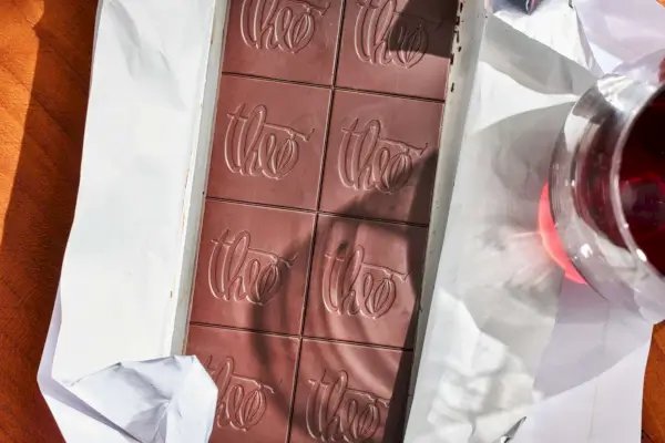 Barra de chocolate amargo Theo 85% desembrulhada sobre uma mesa de madeira