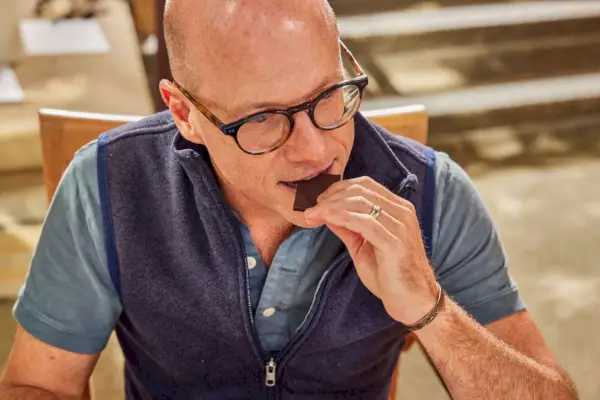 Uma pessoa comendo um pedaço de barra de chocolate amargo Theo 85%