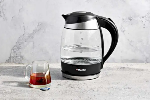 Czajnik Mueller Ultra Kettle jest umieszczony w pobliżu filiżanki herbaty w szklance