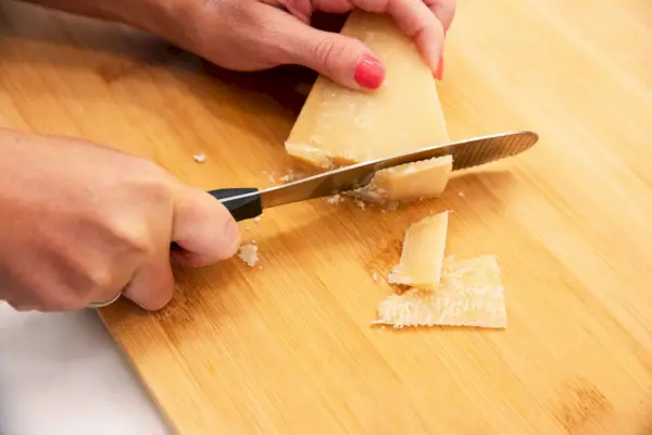 אדם חותך גבינה קשה באמצעות Wüsthof Gourmet 5