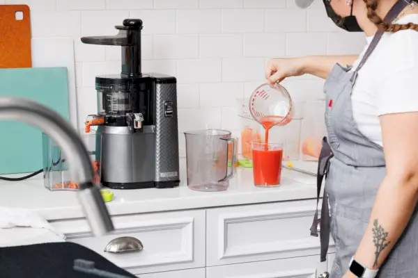 Osoba nalievajúca šťavu vyrobenú v odšťavovači Nama J1 Cold Press Juicer do pohára