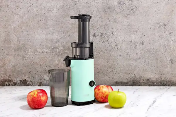 Dash Compact Cold Press Power Juicer zobrazený s jablkami