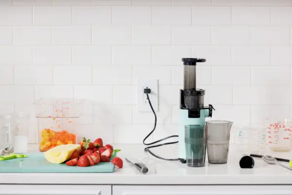 Dash Compact Cold Press Power Juicer vystavený s ovocím a kuchynským príslušenstvom