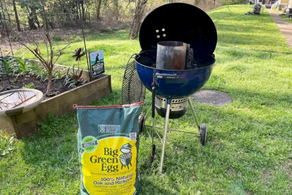 Big Green Egg-Holzkohle aus Natureiche und Hickory-Holzkohle neben einem Grillgerät