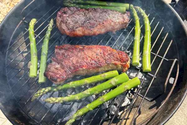 Fleisch und Spargel werden auf einem mit Jealous Devil All Natural Hardwood Lump Charcoal befeuerten Grill gegrillt