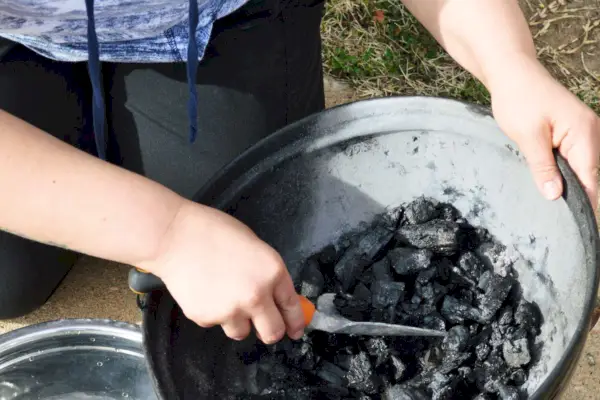 Person pflückt B&B Charcoal Oak Lump Charcoal von einem Grill