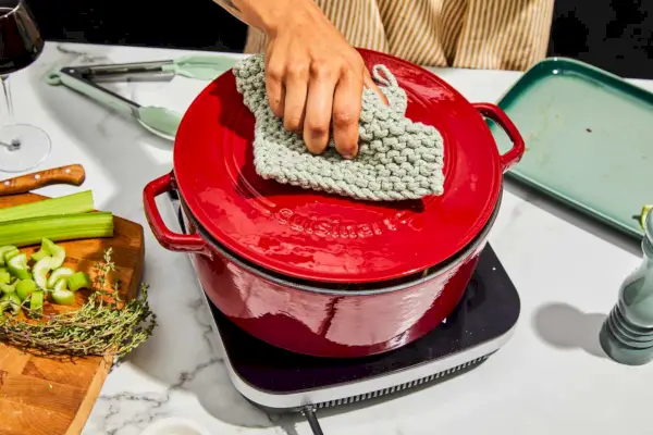 Eine Person benutzt einen Ofenhandschuh, um den Deckel des Cuisinart Chef zu öffnen