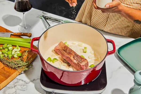 Eine Person, die Fleisch im Cuisinart Chef würzt