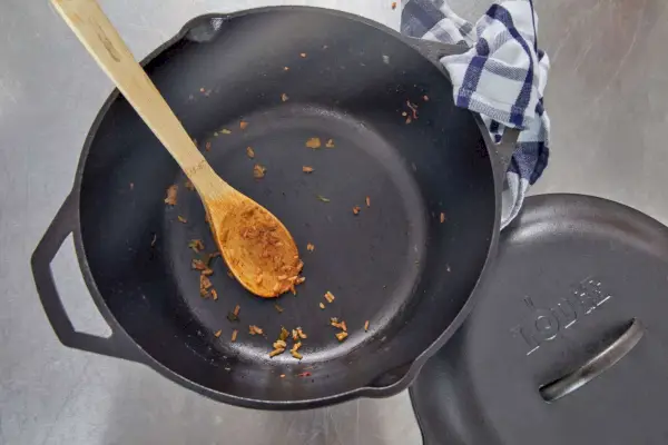 Eine Person öffnet mit Ofenhandschuhen den Deckel des Le Creuset 7,25 qt. Runder holländischer Ofen aus emailliertem Gusseisen