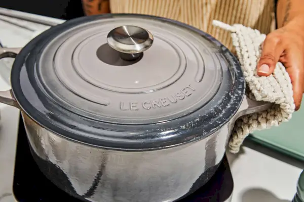 Eine Person hält den Le Creuset 7,25 qt. Runder holländischer Ofen aus emailliertem Gusseisen