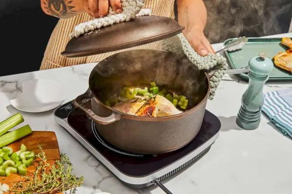 Eine Person öffnet den 5,5-Quart-Dutch-Ofen von Smithey Ironware