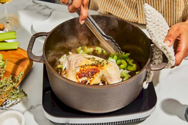 Eine Person, die im Smithey Ironware 5,5-Quart-Dutch-Ofen kocht