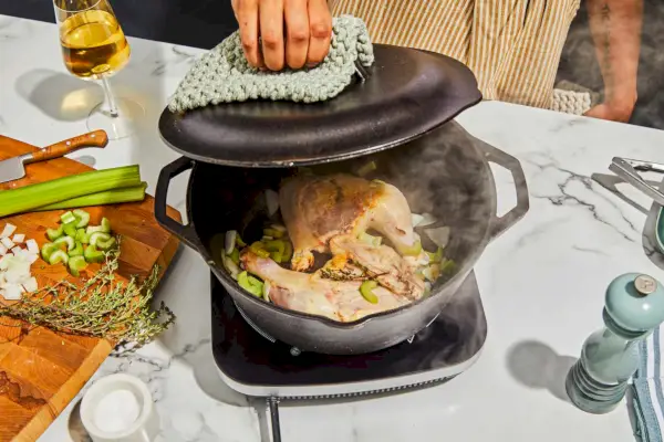 Eine Person öffnet den Lodge 5-Quart Cast Iron Double Dutch Oven