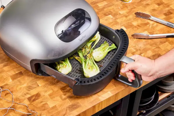 Mano usando una agarradera para sacar una hoja de galletas horneadas del horno tostador Instant Pot Omni Plus Air Fryer