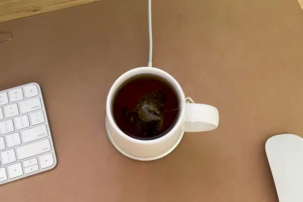Biely samoohrevný keramický hrnček Ohom Ui pripojený na stôl.